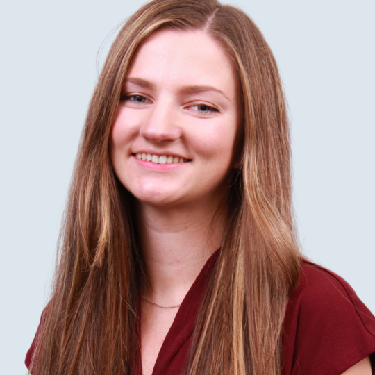 Image of a woman with long brown hair, wearing a maroon shirt